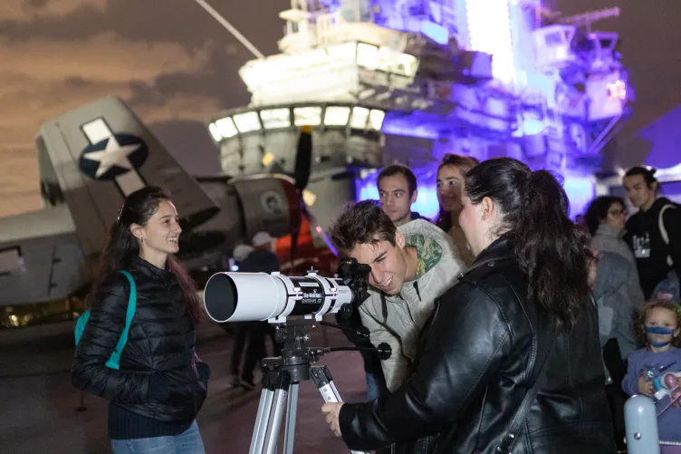 Visitors are looking through a telescope on the flight deck.