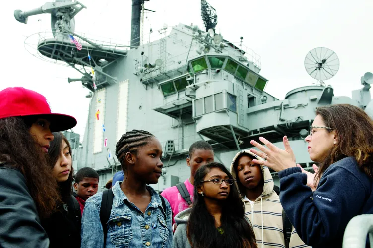 A group of kids are listening to a Museum educator on the flight deck.