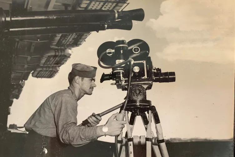 Archival image of an Intrepid sailor with a camera filming