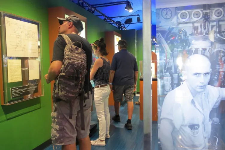 Intrepid after hours hero image - A patron at the intrepid museum reading intently about one of the exhibits