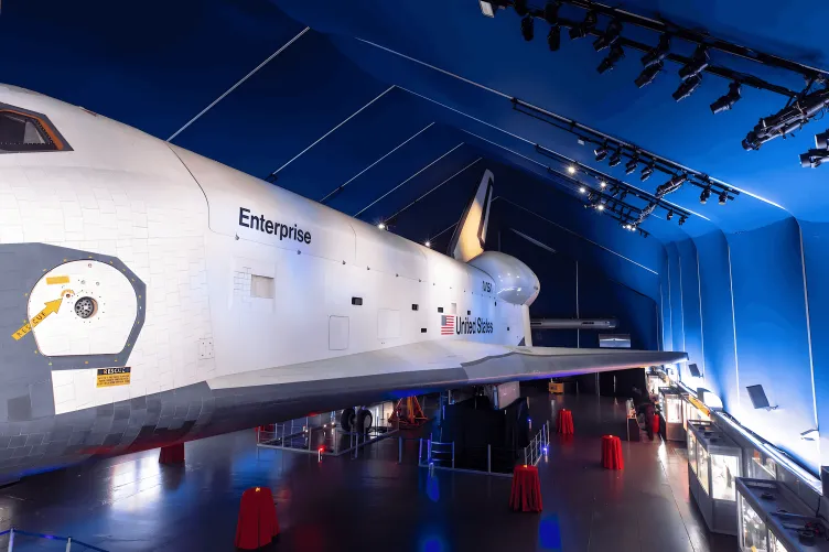 Overview of the Space Shuttle Pavilion with the Enterprise Shuttle, set for a cocktail reception with red linens on cocktail tables