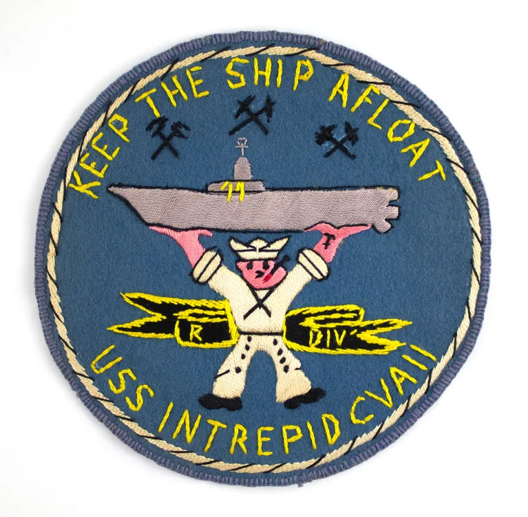 A crew patch that says "Keep the ship afloat, USS Intrepid CVAII" and shows a sailor lifting the ship.