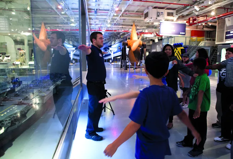 A tour guide with a group of visitors on the Hangar Deck.