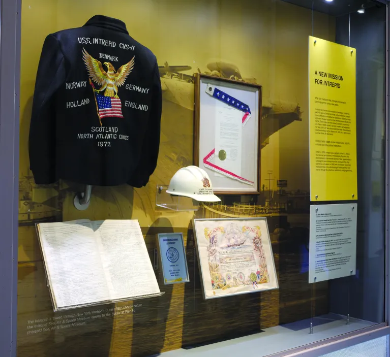 An exhibition case featuring a uniform jacket, a hard hat and several documents.