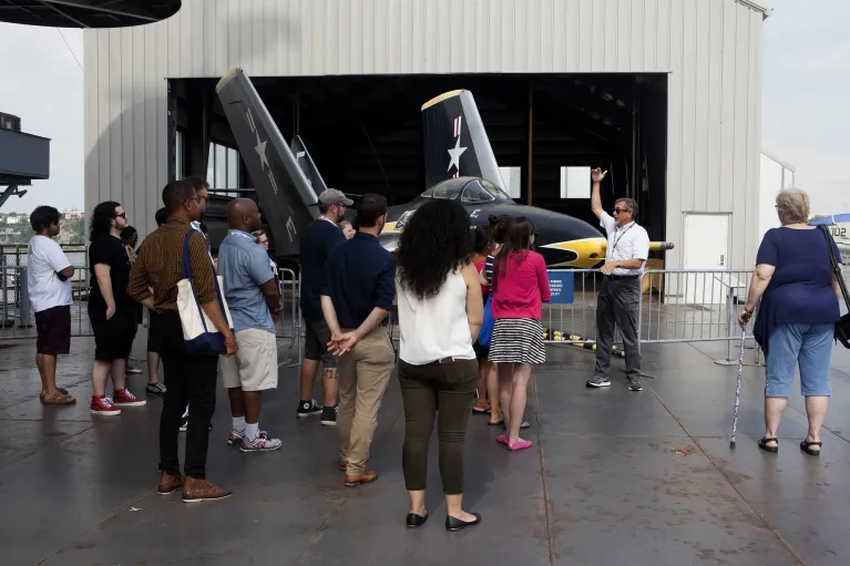 A group of visitors are looking at an airplane outside aircraft restoration