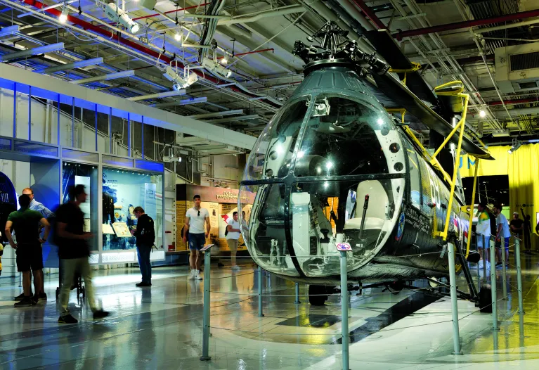 A helicopter on the Museum's hangar deck with visitors in the background.