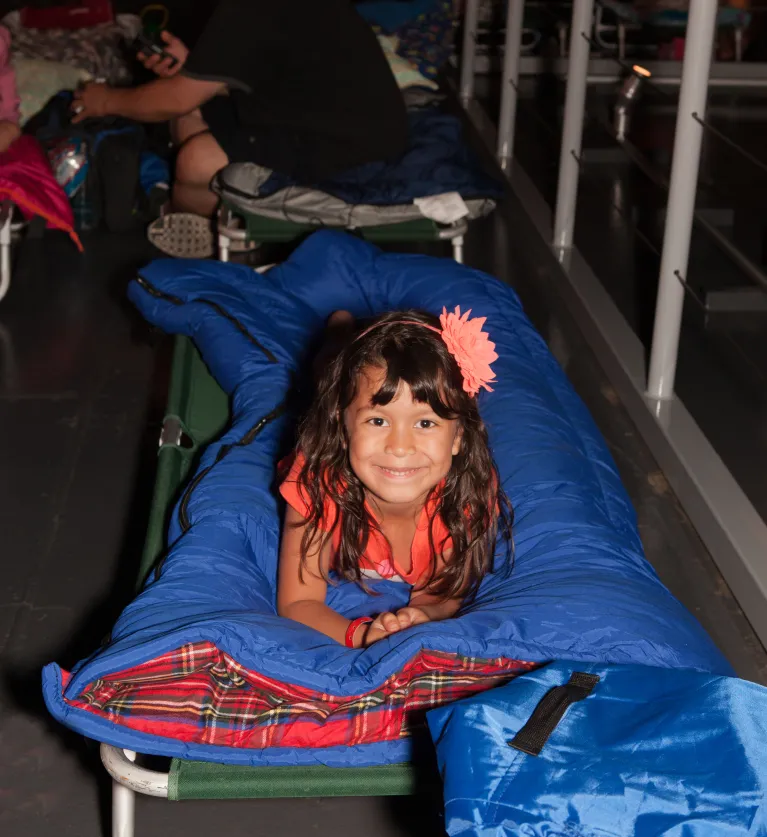 A girl lies down on a sleeping bag while at an overnight at the Museum.