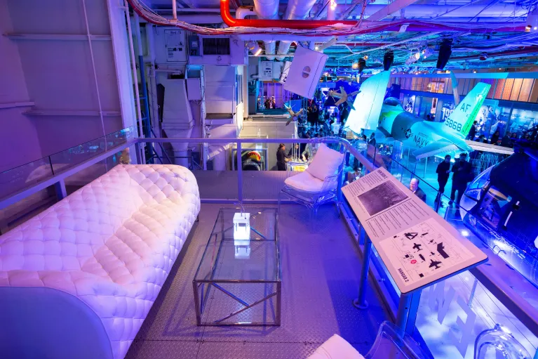 The view deck in Hangar 2 during a reception with white lounge furniture and uplighting in blue
