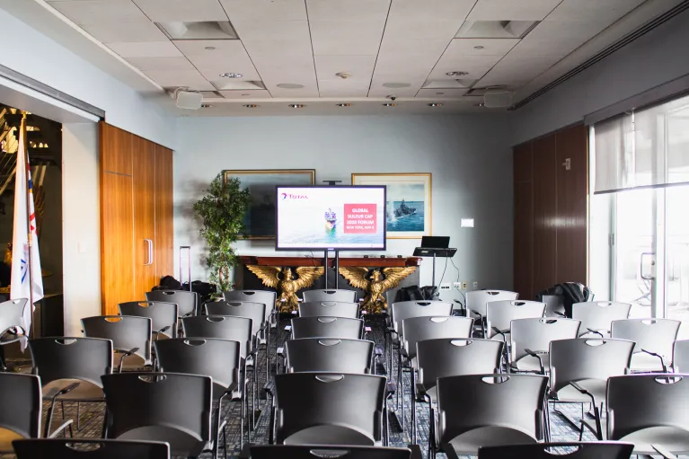 Theater style seating in the VIP Room facing a large monitor screen for a presentation