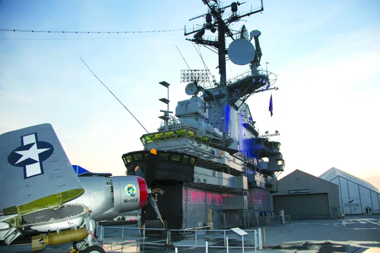 Intrepid’s island rises high above an aircraft parked on the ship's flight deck