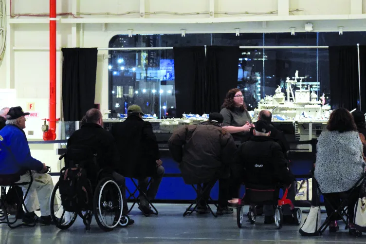 A guide is giving a tour to a group of wheelchair users.