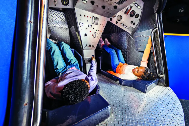 Two children play inside a mock space capsule located in the Museum's Exploreum