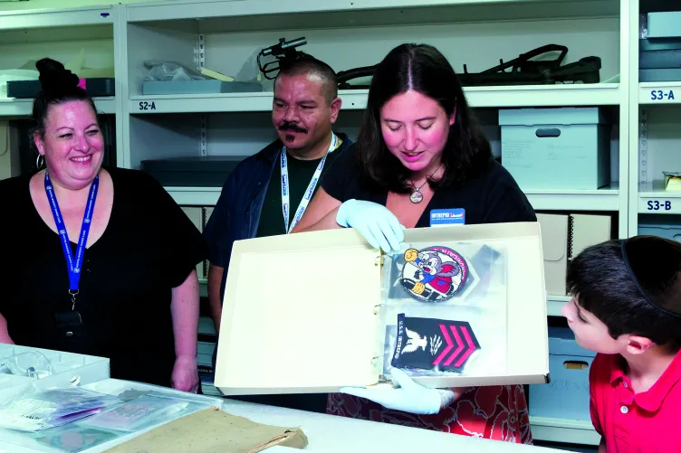 A Museum educator is showing something in a book to visitors