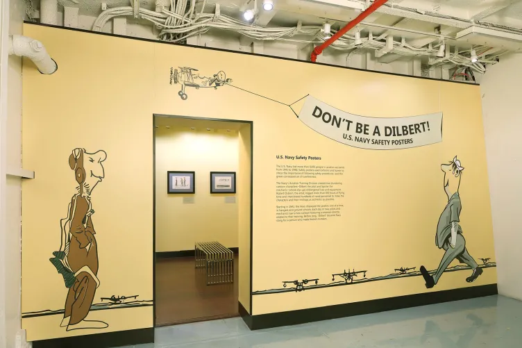The entrance to the “Don’t Be a Dilbert” exhibition and two cartoon characters which were used by the Navy to help train navy personnel.