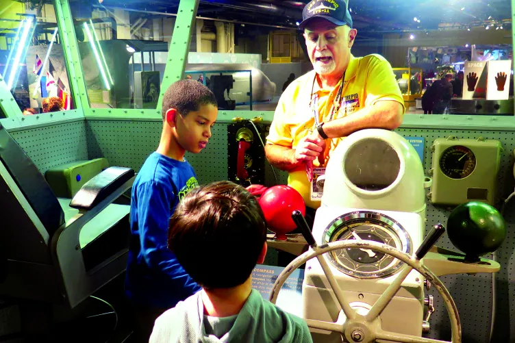 A group of kids are listening to a Museum educator on the flight deck.