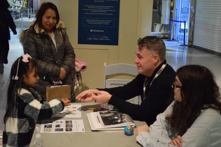 An educator engages with families during an activity at the Intrepid Museum.