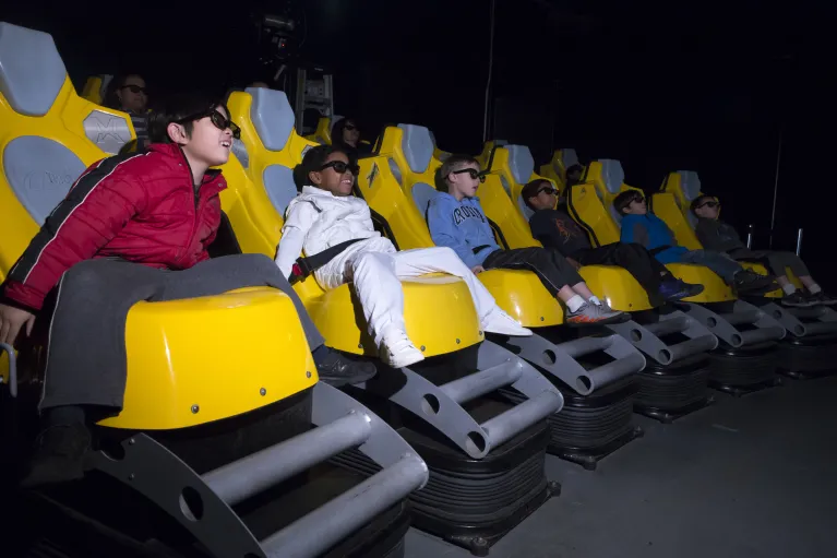Image of children in 3-D glasses enjoying a ride on the 4-D simulator experience, Stories of Intrepid