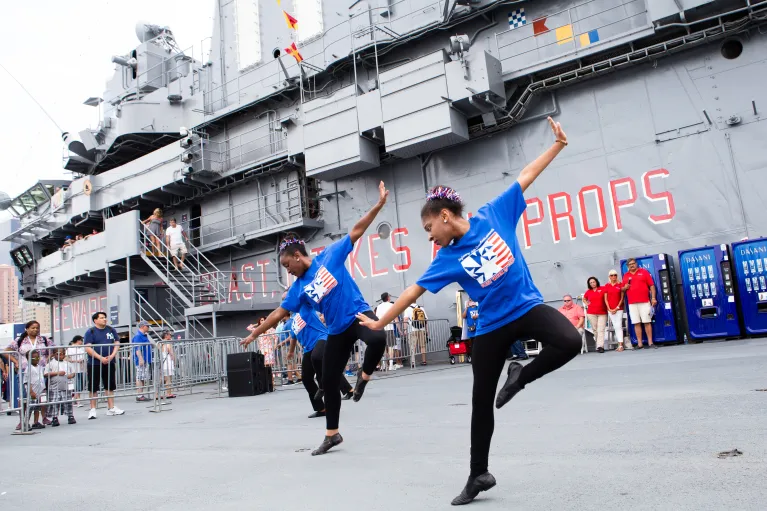 Two members of a dance group perform on the flight deck.