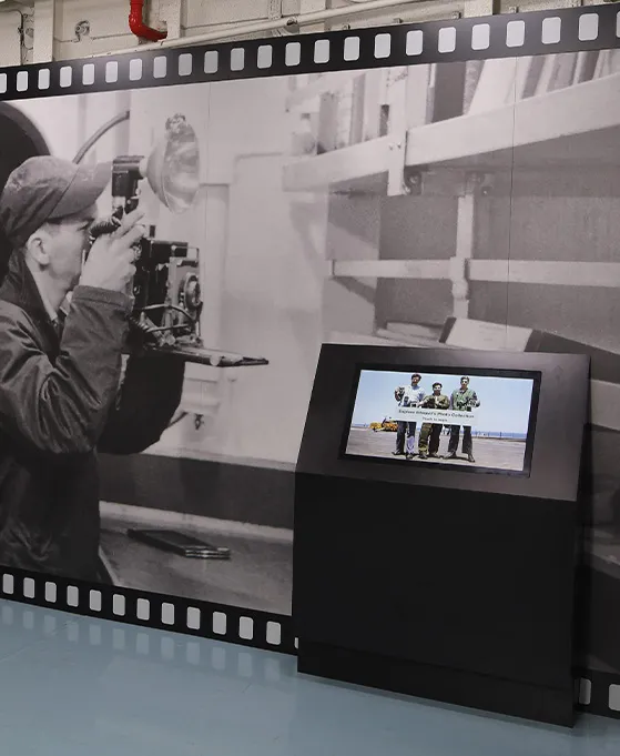 A close up of an exhibition panel designed like a film strip with a video showing excerpts from U.S. Navy training films that show the photographic process.