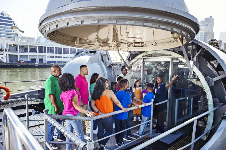 Group of visitors with a museum guide at the entrance of the submarine Growler