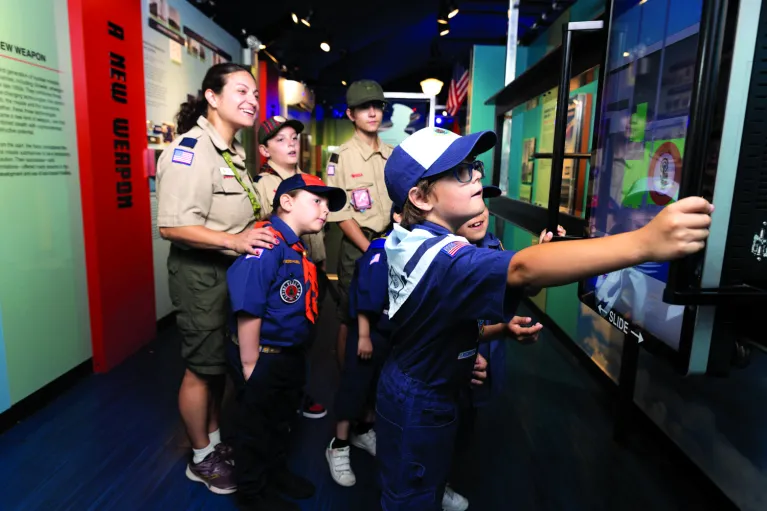 A group of scouts and their leader interacts with an element in the exhibition, A View From the Deep: The Submarine growler and the Cold War.