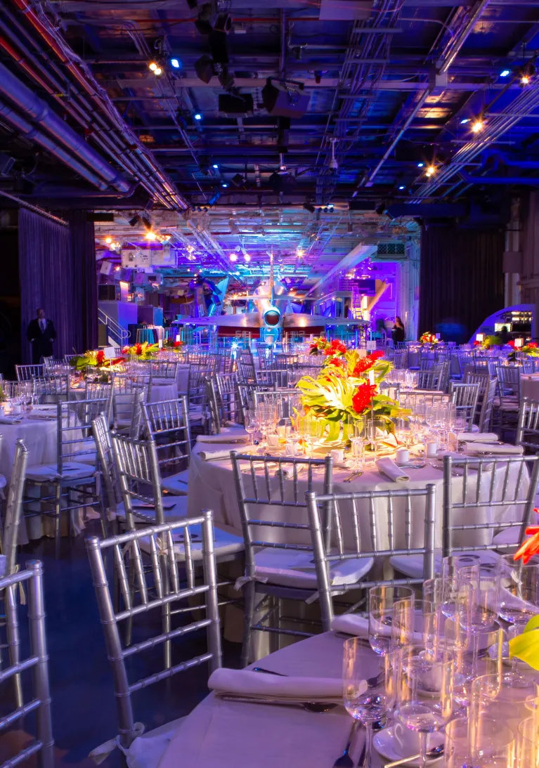 Tables set up for a party with decorations on an aircraft carrier.