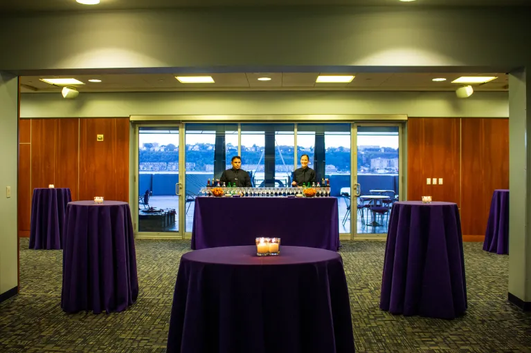 Hightop tables with purple linen and bar for a cocktail reception
