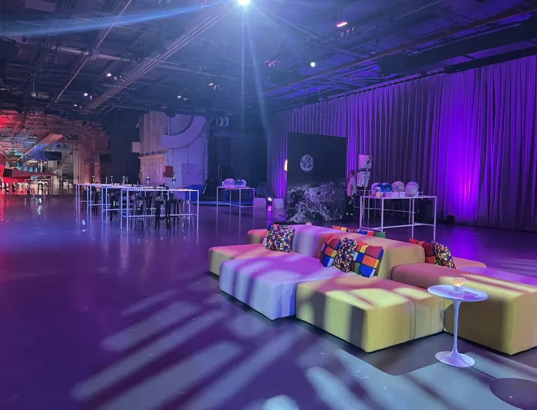 Colorful lounge setup in Hangar 3 with high top tables and purple lighting