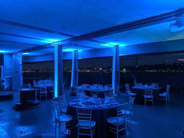 Fantail set for a seated dinner at sunset with blue uplighting