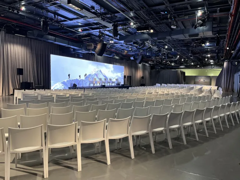 Conference setup in Hangar 3 with theater style seating and a large LED screen for the program