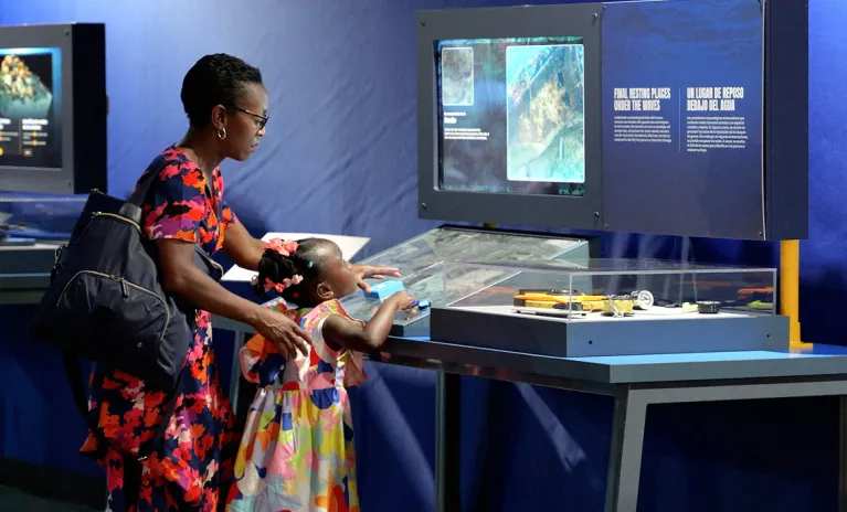 A woman and young girl interacting with a hands-on element from the Mysteries from the Deep exhibition during the opening event.