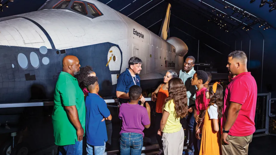 Group of visitors with a museum guide in front of the Space Shuttle Enterprise