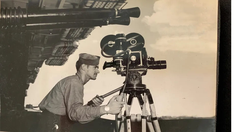 Archival image of an Intrepid sailor with a camera filming